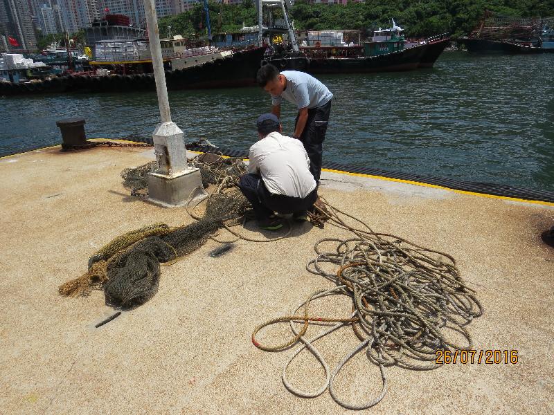 Agriculture, Fisheries and Conservation Department (AFCD) officers intercepted a trawler suspected to be operating illegally in the waters off Yuen Kok of Lamma Island during an anti-illegal fishing operation today (July 26). Picture shows AFCD officers handling the fishing gear including fishing nets and ropes seized on board the vessel.