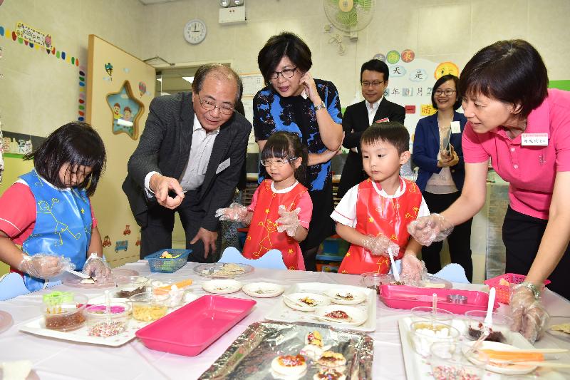 The Secretary for Education, Mr Eddie Ng Hak-kim (second left), observes students making snacks during his visit to Po Leung Kuk Li Tsui Chung Sing Memorial Kindergarten today (August 29).