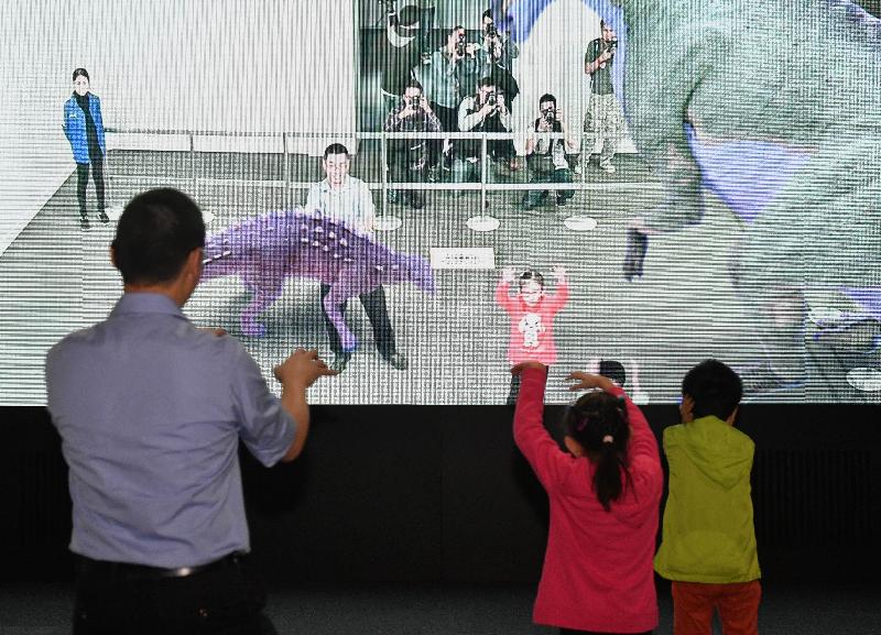 「超感官暴龍展」今日（十二月一日）於香港科學館揭幕。圖示展品「回到侏羅紀」，在大型屏幕前，參觀者可跟體型原大的巨型梁龍一起互動，或輕撫草食性禽龍，享受一個獨一無二的體驗。