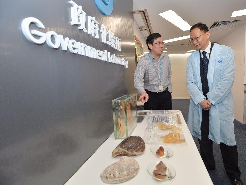 While visiting the Trade Descriptions Section of the Government Laboratory today (December 5), the Secretary for the Civil Service, Mr Clement Cheung (right), is briefed by staff on how they conduct authenticity tests on consumer products.