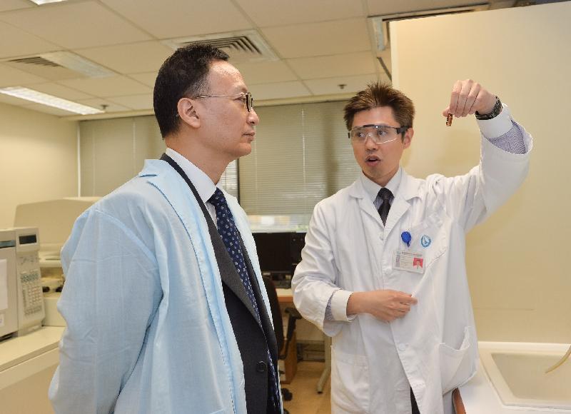 While touring the Additives, Contaminants and Composition Section of the Government Laboratory today (December 5), the Secretary for the Civil Service, Mr Clement Cheung (left), is briefed on the process of sample preparation and analysis.