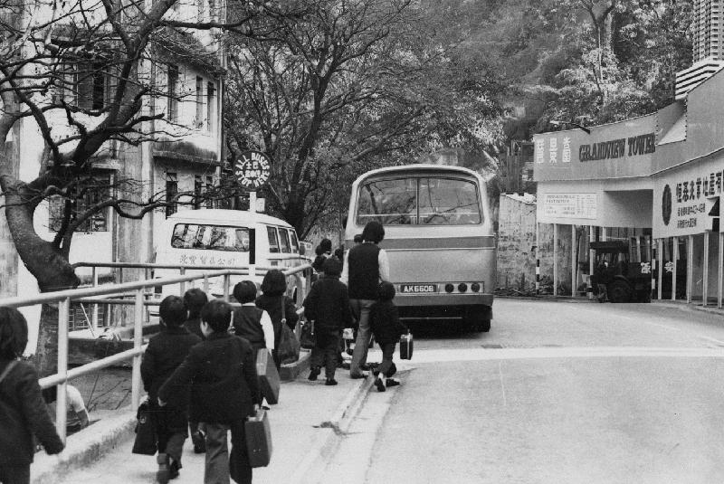 「沿途風光好：1970年代香港島巴士站街景照片展」的其中一幀圖片：一九七七年學生挽着流行一時的書喼。