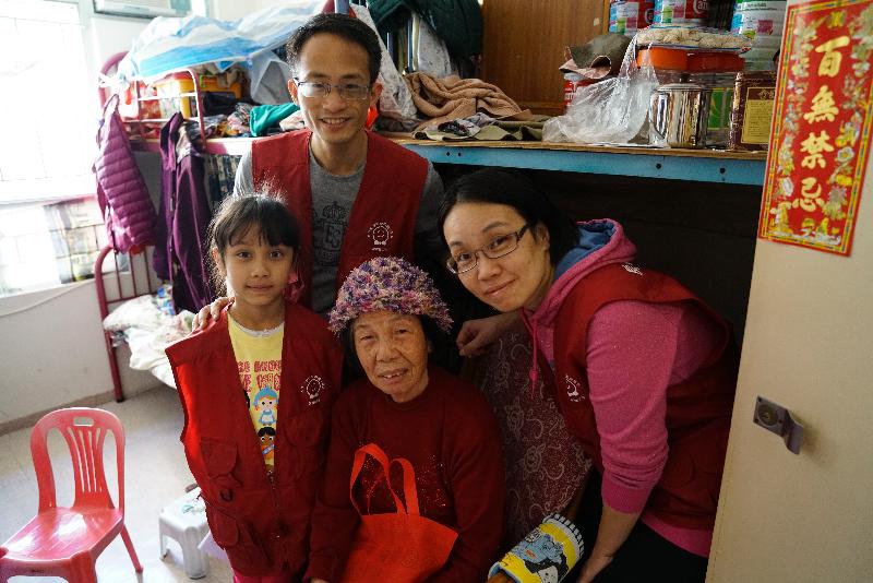 Members of the Housing Department Volunteers Corps present an elderly lady with a knitted hat and a lucky bag during a visit to Shek Lei (2) Estate in Kwai Tsing on December 10.
