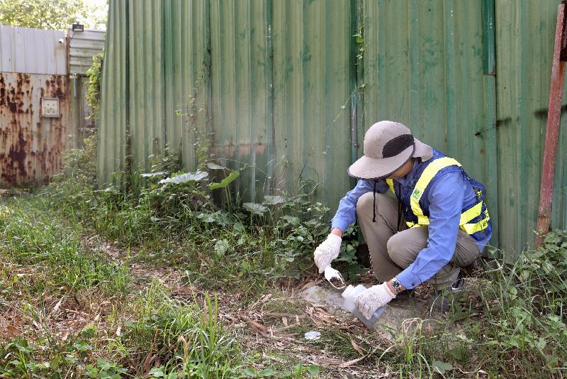 During a joint departmental enforcement operation entitled "Operation E-change" held in mid-December, the Environmental Protection Department (EPD) and relevant departments conducted surprise inspections at a number of open waste recycling sites in Yuen Long. A staff member of the EPD takes water and soil samples nearby to see whether the recycling site operations have affected the surrounding environment.


