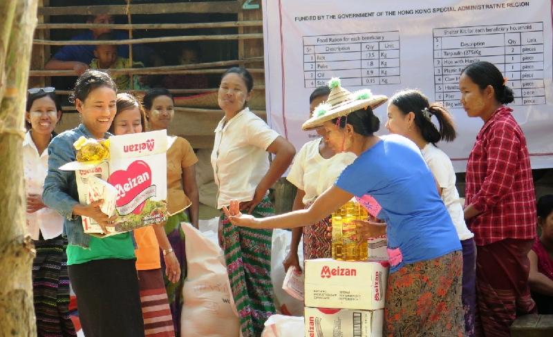 Local staff of the relief organisation pass food packs, which contain rice, pulses, cooking oil and salt, to flood victims in Myanmar.