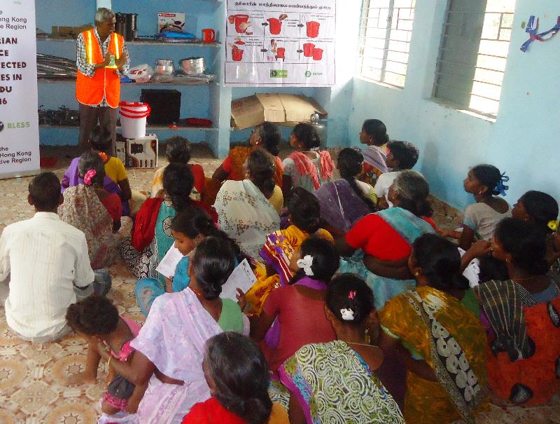A local staff member of the relief organisation provides a briefing for flood victims in India on the safety concerns of using water and sanitation items.