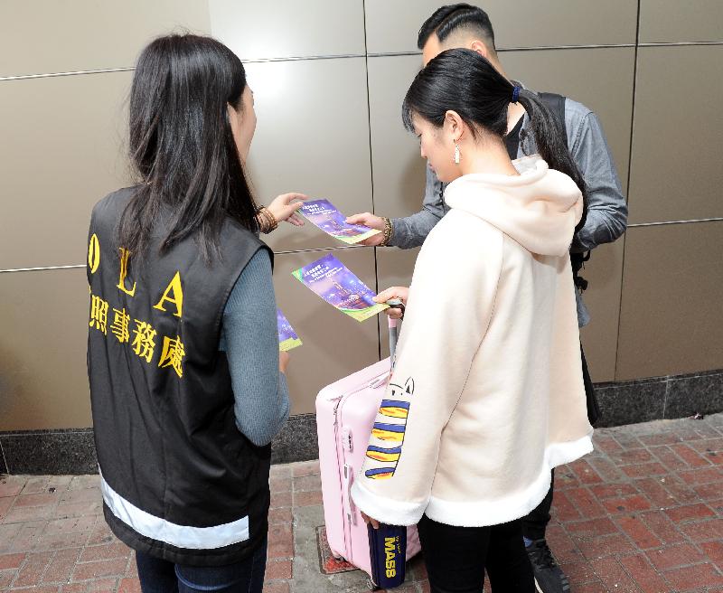 Staff of the Office of the Licensing Authority (OLA) of the Home Affairs Department distribute pamphlets to tourists to encourage them to report any information about unlicensed guesthouses to the OLA.