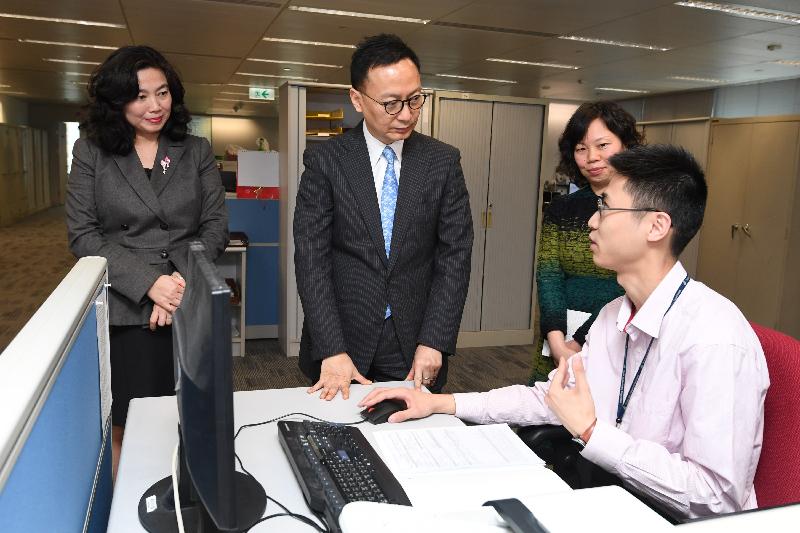 公務員事務局局長張雲正（左二）今日（三月二十四日）在工業貿易署觀看職員示範如何處理戰略物品的牌照申請。