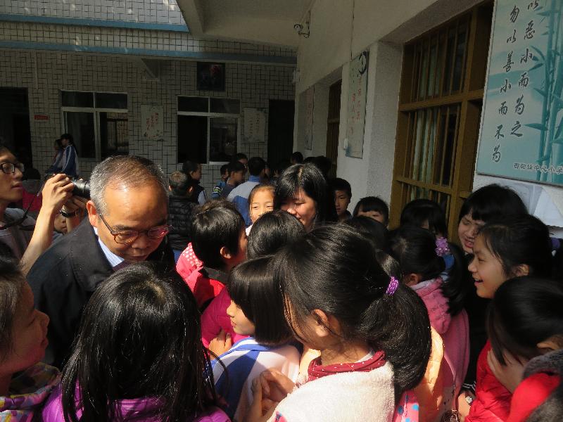 The Secretary for Home Affairs, Mr Lau Kong-wah, visited Meizhou from yesterday (March 27) to today (March 28) to meet with the delegates of the Service Corps programme providing voluntary teaching assistance there. Photo shows Mr Lau (first left) talking to delegates and pupils at Xiyang Town Centre Primary School today.