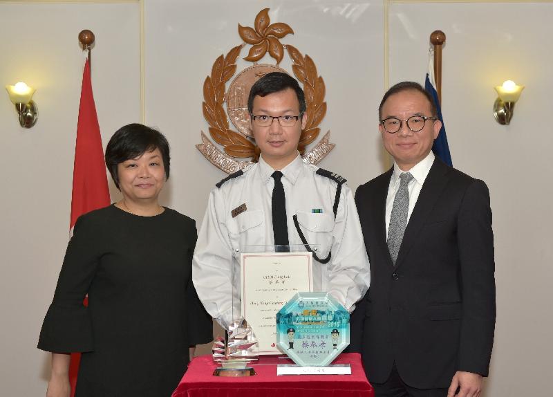 The Senior Manager of Corporate Communications of the Hong Kong Tourism Board, Ms Jane Ha (left), and the Director of Immigration, Mr Tsang Kwok-wai (right), present awards and a souvenir to the most courteous Immigration control officer, Mr Choi Fung-hau, today (April 12).