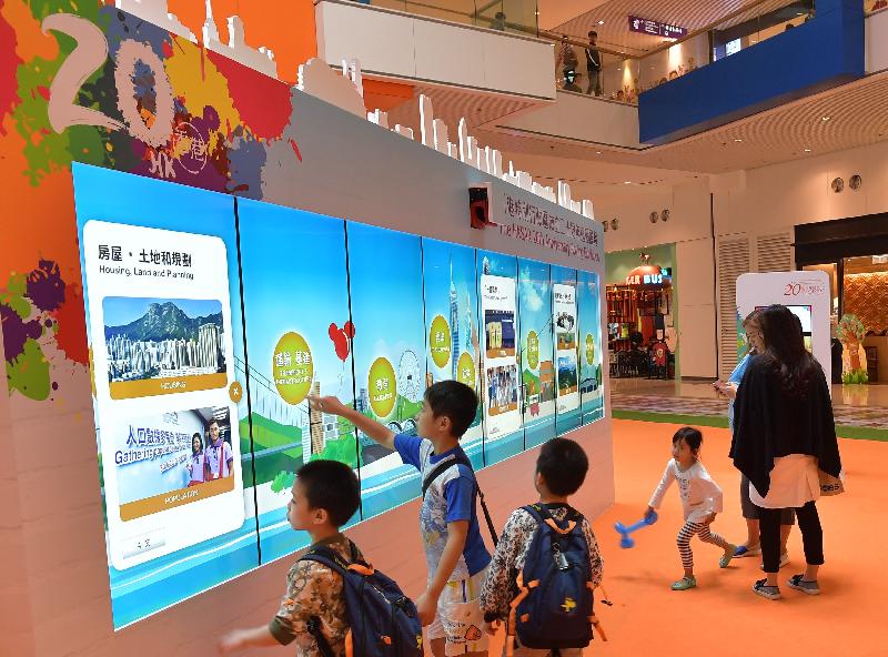 學生瀏覽巨型電子顯示屏幕上有關香港過去二十年發展和成就的照片。
