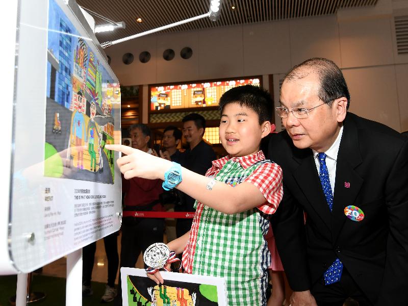 Winning primary student of the HKSAR 20th Anniversary Poster Design Competition today (April 14) shares his creative concept with the Chief Secretary for Administration, Mr Matthew Cheung Kin-chung.