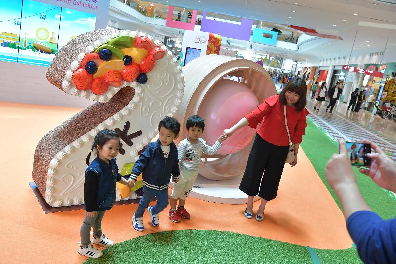 Members of the public pose for photos in front of the installations displayed at the HKSAR 20th Anniversary Roving Exhibition today (April 14).