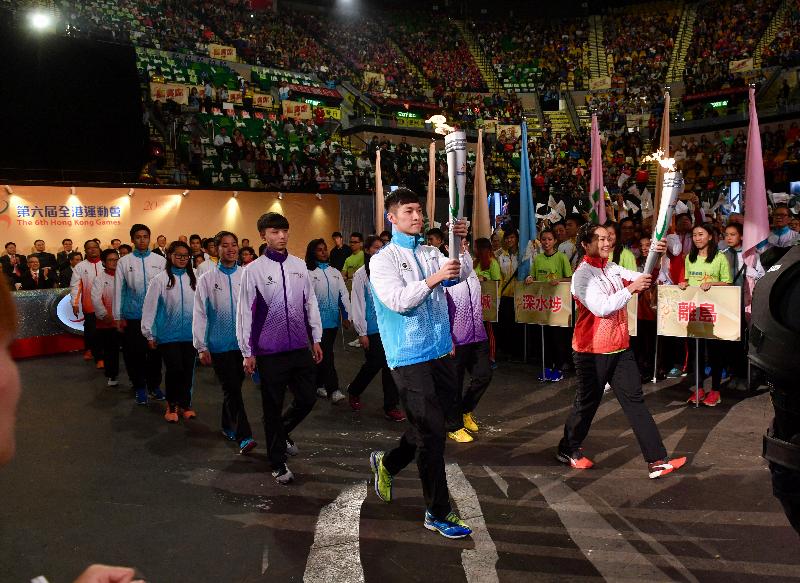 Hong Kong elite athletes Sarah Lee (front row, second left) and Angus Ng (front row, first left), holding the torch, lead the athletes representing the 18 districts into the Coliseum at the 6th Hong Kong Games Opening Ceremony today (April 23).