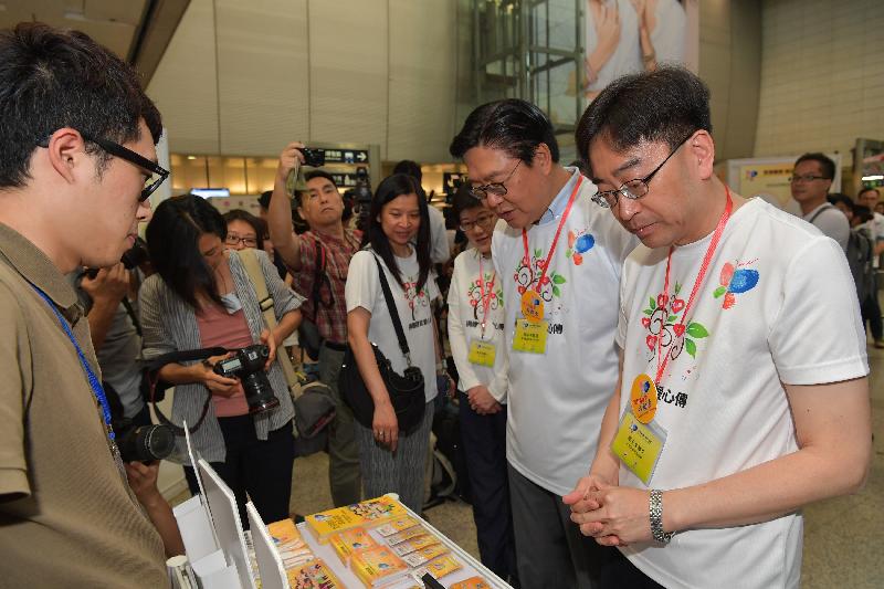 負責「全城響應　器官捐贈」推廣運動展覽所設的推廣攤位的義工（左一）今日（五月六日）向食物及衞生局局長高永文（右一）和香港鐵路有限公司主席馬時亨教授（右二）介紹宣傳品。