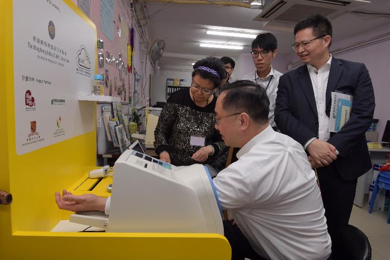 创新及科技局局长杨伟雄（中）今日（五月十二日）下午到访南葵涌社会服务处时，试用电子健康站量度血压。