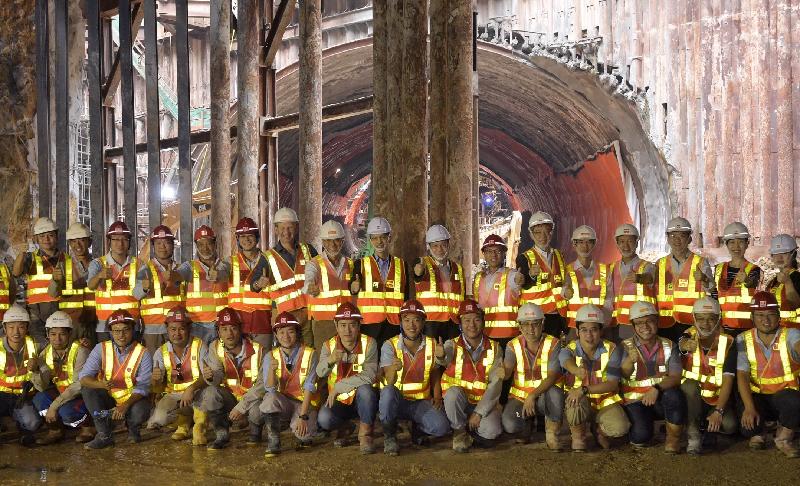 The Secretary for Transport and Housing, Professor Anthony Cheung Bing-leung (back row, eighth right), accompanied by the Director of Highways, Mr Daniel Chung (back row, ninth right), gives his encouragement to the project team and frontline workers at the works site of the Scenic Hill Tunnel section of the Hong Kong-Zhuhai-Macao Bridge Hong Kong Link Road (HKLR) today (May 18). The last unit of the tunnel box segment in the Scenic Hill Tunnel section of the Hong Kong-Zhuhai-Macao Bridge HKLR was jacked into its final position underneath the Airport Express Line on May 16, with all the tunnel excavation works completed. Together with the completion of the connection of the HKLR viaduct section in March this year, the 12 kilometre-long HKLR is now completely connected.