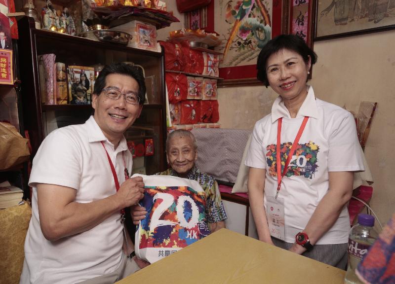 商務及經濟發展局局長蘇錦樑（左一）和香港聖公會福利協會總幹事李正儀博士（右一）今日（六月二日）到中西區探訪長者，並向她派發「二十周年慶祝活動禮物包」，共慶回歸。