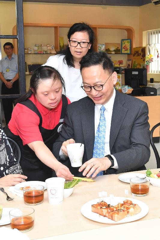 While touring the café of the SAHK LOHAS Garden today (June 9), the Secretary for the Civil Service, Mr Clement Cheung (right), experiences the catering services provided by trainees.