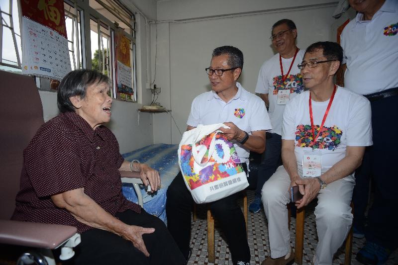 The Financial Secretary, Mr Paul Chan, conducted home visits in Sai Kung District under the "Celebrations for All" project today (June 14). Photo shows Mr Chan (second right) chatting with a family member and presenting her with a gift pack to share the joy of the 20th anniversary of the establishment of the Hong Kong Special Administrative Region.