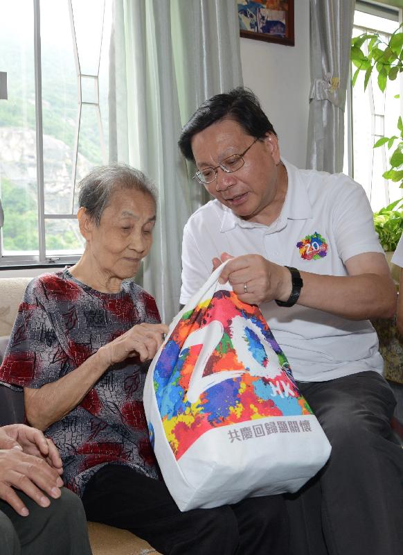 The Secretary for Transport and Housing, Professor Anthony Cheung Bing-leung (right), visits the elderly in Shau Kei Wan under the "Celebrations for All" project today (June 17). Picture shows Professor Cheung giving a gift pack to the elderly to share the joy of the 20th anniversary of the establishment of the Hong Kong Special Administrative Region. 
