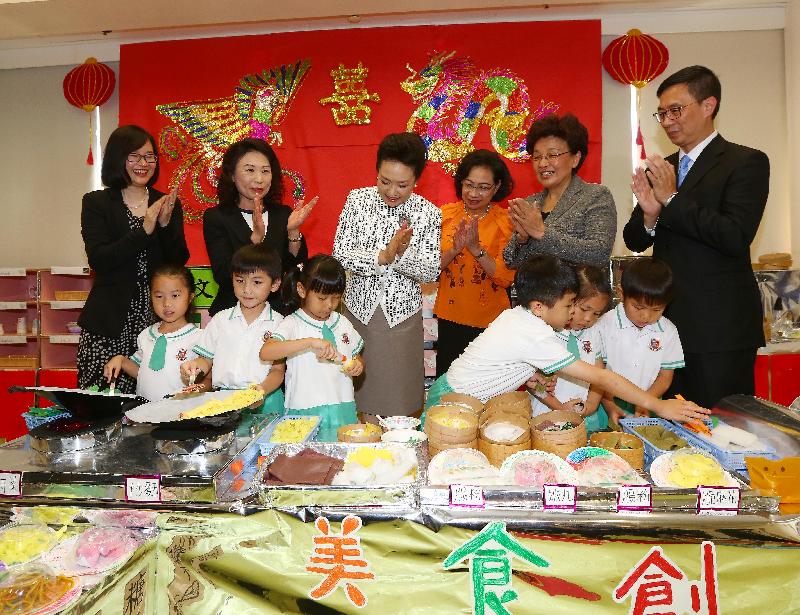 The wife of President Xi Jinping, Peng Liyuan (third left), accompanied by the wife of the Chief Executive, Mrs Regina Leung (third right), observes kids playing dim sum games at Yau Yat Chuen School today (June 29). Looking on are the Under Secretary for Education, Mr Kevin Yeung (first right); Deputy Director of the Liaison Office of the Central People's Government in the Hong Kong Special Administrative Region Ms Yin Xiaojing (second right); and the kindergarten's principal, Ms Lee Ming-chu (second left).