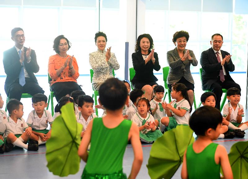 The wife of President Xi Jinping, Peng Liyuan (third left), accompanied by the wife of the Chief Executive, Mrs Regina Leung (second left), watches performances by students at Yau Yat Chuen School today (June 29). Looking on are the Under Secretary for Education, Mr Kevin Yeung (first left); the Chairman of the kindergarten's School Management Committee, Mr Yu Kwok-chun (first right); Deputy Director of the Liaison Office of the Central People's Government in the Hong Kong Special Administrative Region Ms Yin Xiaojing (second right); and the kindergarten's principal, Ms Lee Ming-chun (third right). 