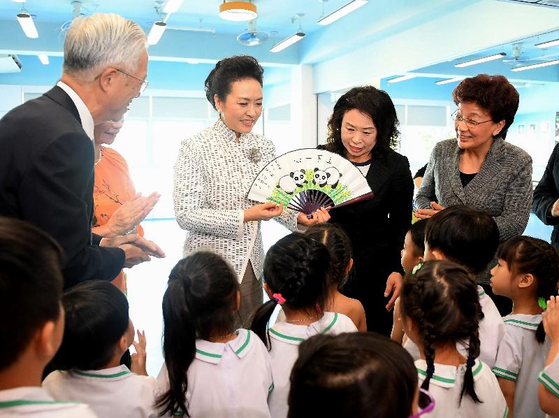 The wife of President Xi Jinping, Peng Liyuan (third right), visits Yau Yat Chuen School today (June 29) and is presented by students a fan with hand-painted pandas as a souvenir. Looking on are Deputy Director of the Liaison Office of the Central People's Government in the Hong Kong Special Administrative Region Ms Yin Xiaojing (first right) and the kindergarten's principal, Ms Lee Ming-chu (second right).