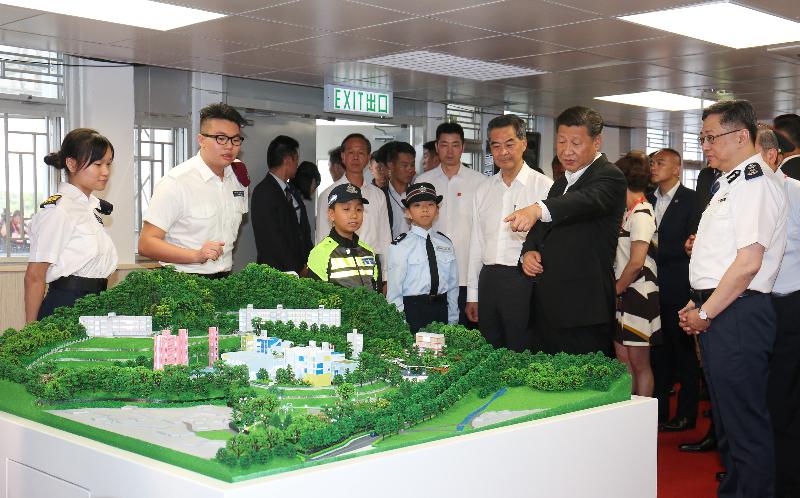President Xi Jinping (second right) views a model of the Junior Police Call (JPC) Permanent Activity Centre and Integrated Youth Training Camp while being briefed by a JPC member on the facilities and training concept during his visit to the Training Camp today (June 30). Looking on are the Chief Executive, Mr C Y Leung (third right), and the Commissioner of Police, Mr Lo Wai-chung (first right).