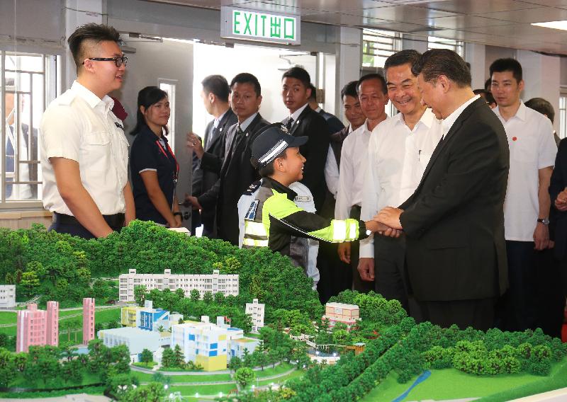 President Xi Jinping (first right) today (June 30) shakes hands and chats with a Junior Police Call (JPC) member after viewing a model at the JPC Permanent Activity Centre and Integrated Youth Training Camp. Looking on is the Chief Executive, Mr C Y Leung (second right).