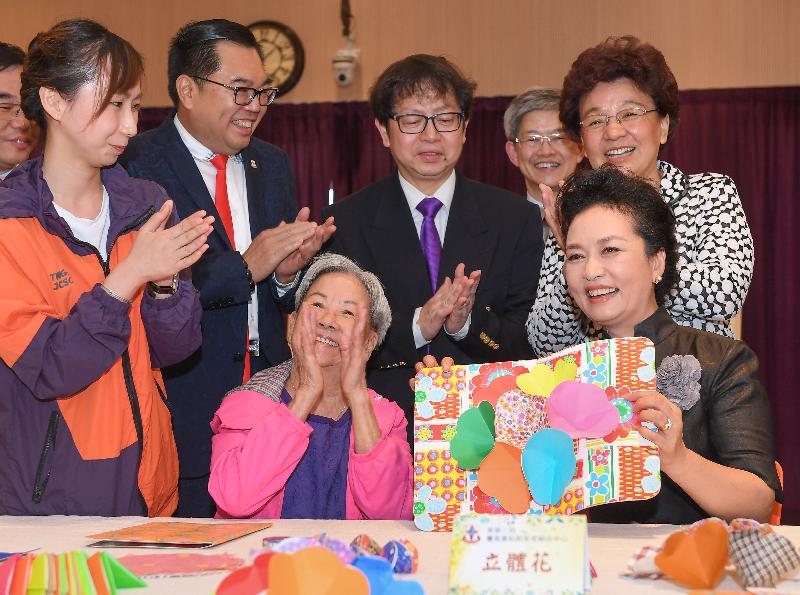 The wife of President Xi Jinping, Peng Liyuan (front row, right), shows her appreciation to an elderly lady in making a pop-up card during her visit to TWGHs Jockey Club Sunshine Complex for the Elderly in Wong Chuk Hang this morning (June 30). Those joining her in the visit include Deputy Director of the Liaison Office of the Central People's Government in the Hong Kong Special Administrative Region, Ms Yin Xiaojing (second row, first right); the Secretary for Labour and Welfare, Mr Stephen Sui (second row, second right); and the Chairman of the Tung Wah Group of Hospitals, Dr Lee Yuk-lun (second row, second left).
