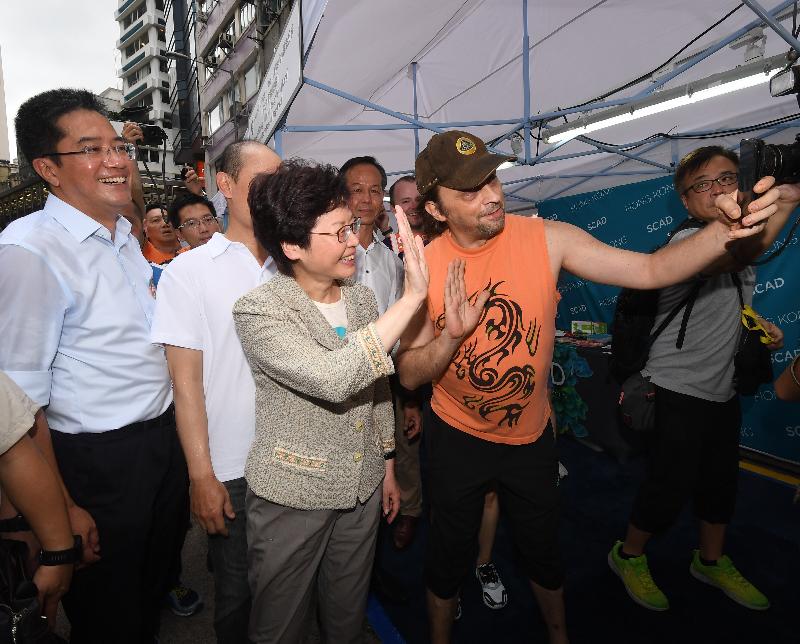 The Chief Executive, Mrs Carrie Lam (centre), takes a photo with a member of the public at the "Heritage Vogue · Hollywood Road" street carnival at Central today (July 2). Looking on is the Secretary for Development, Mr Michael Wong (first left).