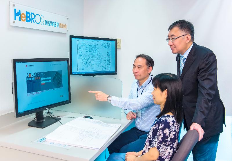 The Head of the Independent Checking Unit, Mr Chan Nap-ming (right), is informed by the supporting team of the Housing Electronic Building Records Online System that zero downtime for the system has been achieved since its launch in December 2014.