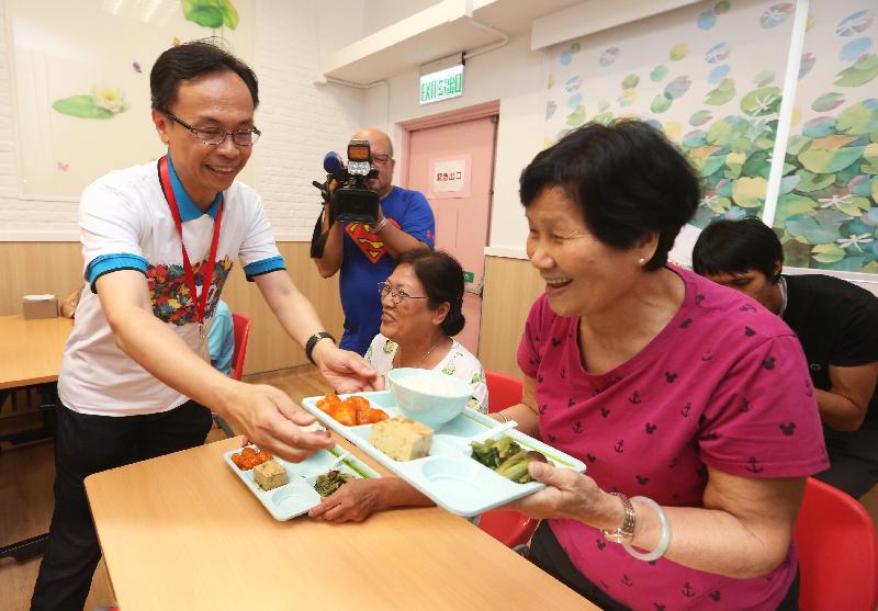 The Secretary for Constitutional and Mainland Affairs, Mr Patrick Nip (left), serves lunch to an elderly person at the Po Leung Kuk Lau Chan Siu Po District Elderly Community Centre today (July 18). 
