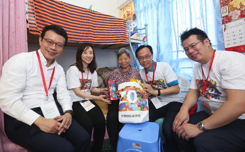 The Secretary for Constitutional and Mainland Affairs, Mr Patrick Nip (second right), accompanied by the Deputy Secretary for Constitutional and Mainland Affairs, Miss Charmaine Lee (second left), and the District Officer (Kwun Tong), Mr Steve Tse (first right), visits an elderly family in Kwun Tong District today (July 18) under the "Celebrations for All" project. Photo shows Mr Nip giving a gift pack to an elderly person.