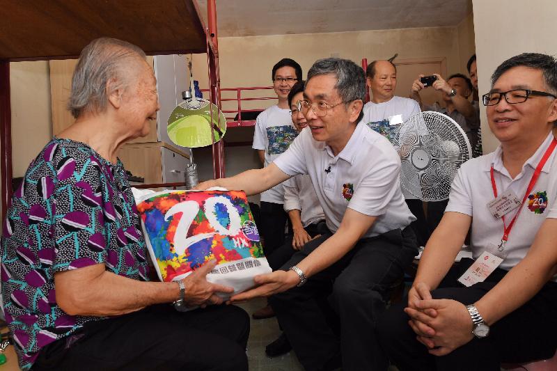 The Secretary for Financial Services and the Treasury, Mr James Lau (centre), gives a gift pack to an elderly resident during his home visits at Shek Pai Wan Estate in Southern District under the "Celebrations for All" project this morning (July 19).