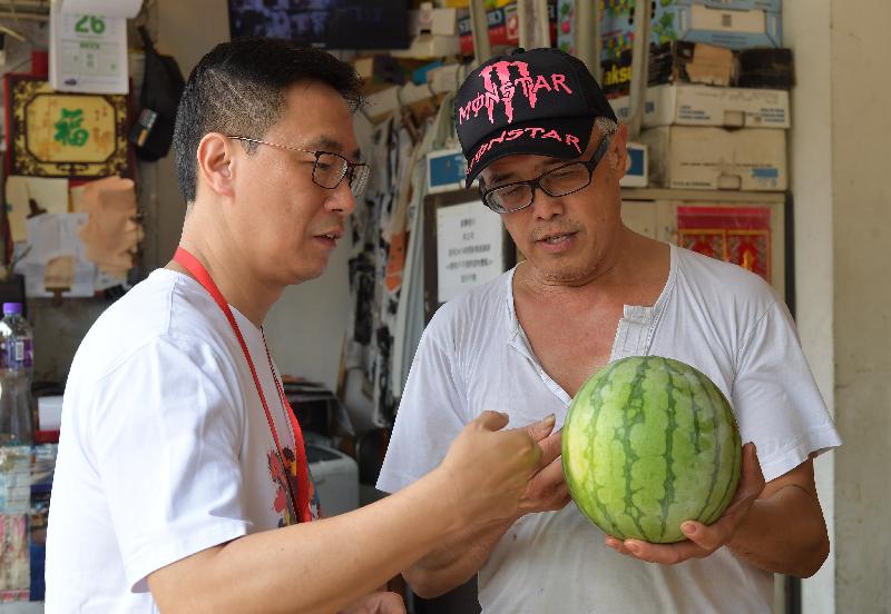 教育局局长杨润雄（左）今日（七月二十五日）进行家访，先到油麻地一间地区小店选购水果，趁机了解区内商店的经营情况。

