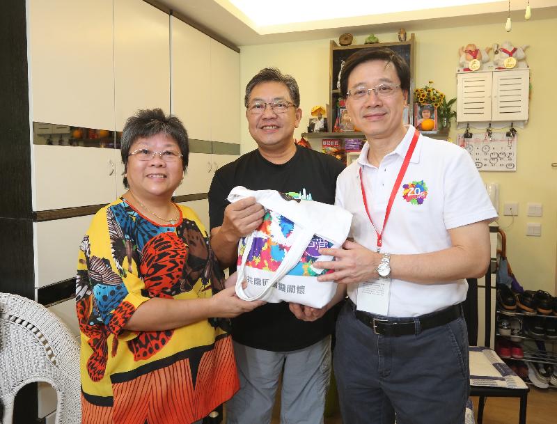 保安局局长李家超（右一）今日（七月二十六日）在欣安邨向一个家庭送上香港回归二十周年礼物包。