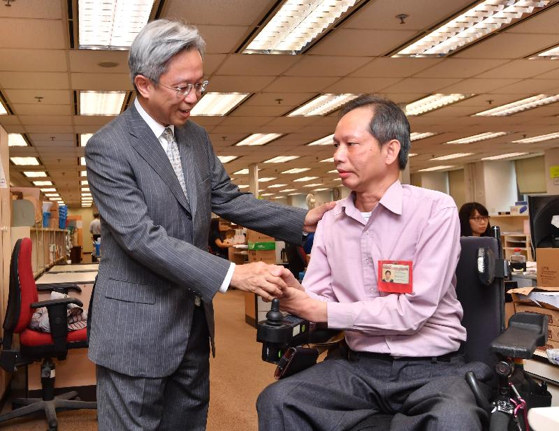公務員事務局局長羅智光（左）今日（八月七日）在稅務局與殘疾同事交談，了解稅務局為幫助殘疾人員融入工作環境所提供的協助。