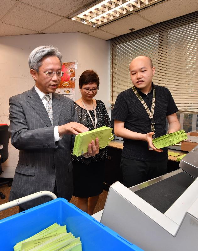 The Secretary for the Civil Service, Mr Joshua Law (left), learns about the handling of tax returns by staff while touring the Document Processing Centre of the Inland Revenue Department today (August 7).