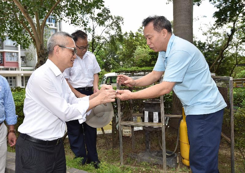 The Under Secretary for Food and Health, Dr Chui Tak-yi (left), inspected mosquito control measures in Tin Shui Wai today (August 12). A Housing Department staff briefed him about the function of a mosquito trapping device installed in the estate.