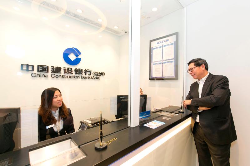 The Chief Executive of the Hong Kong Monetary Authority, Mr Norman Chan (right), in Tin Shui Wai today (August 17) is told about the situation of branch services by staff of China Construction Bank (Asia).