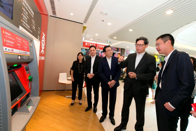 東亞銀行執行董事兼副行政總裁李民橋（右一）今日（八月十七日）在天水圍向香港金融管理局總裁陳德霖（右二）介紹無卡自動櫃員機提款服務。