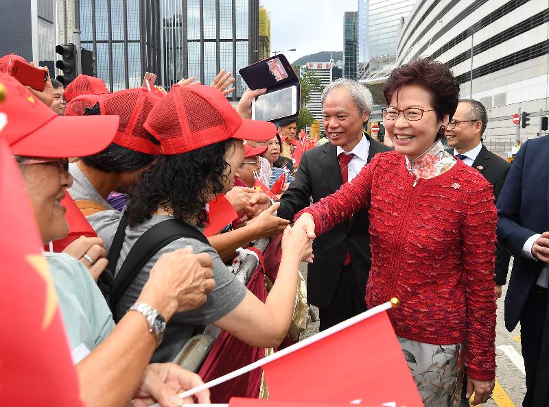 The Chief Executive, Mrs Carrie Lam (first right), greets members of the public before attending the flag-raising ceremony in celebration of the 68th anniversary of the founding of the People's Republic of China at Golden Bauhinia Square in Wan Chai this morning (October 1). Joining her is her husband Dr Lam Siu-por (second right).

