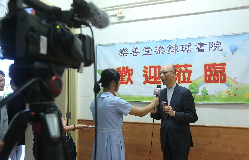 The Secretary for the Environment, Mr Wong Kam-sing (right), today (October 4) visits Lok Sin Tong Leung Kau Kui College. Picture shows Mr Wong being interviewed by a student reporter of the school.