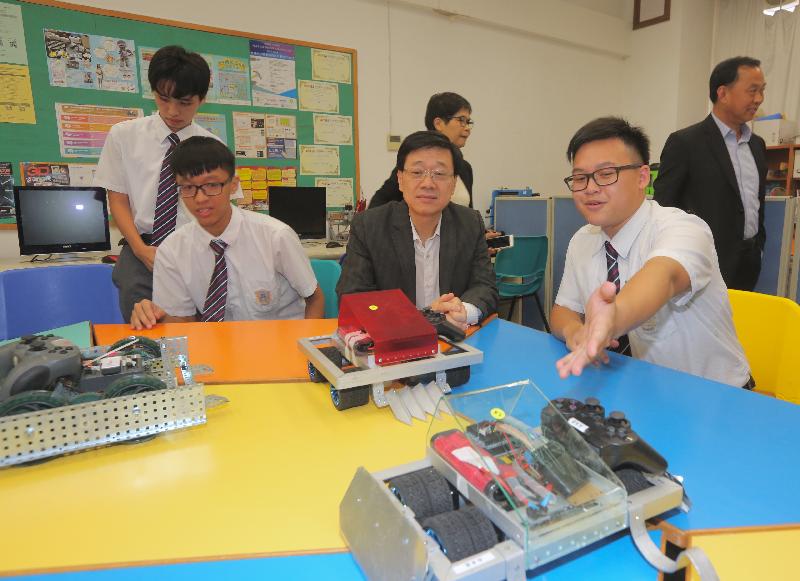 The Secretary for Security, Mr John Lee (centre), is briefed by students on the robots they designed during his visit to the HK & Kowloon Chiu Chow Public Association Secondary School this afternoon (October 10).