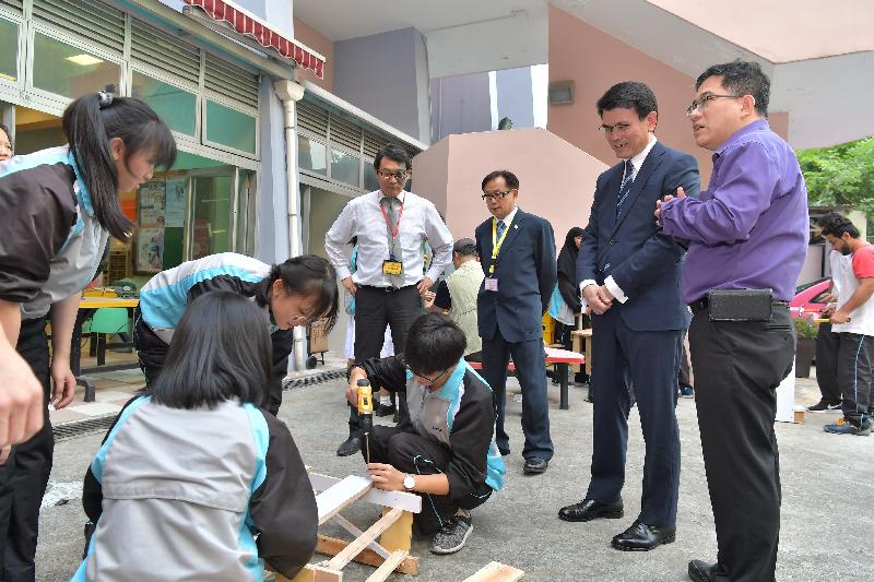 The Secretary for Commerce and Economic Development, Mr Edward Yau (second right), visited Chung Sing Benevolent Society Mrs Aw Boon Haw Secondary School during his visit to Tuen Mun District today (October 24). Picture shows Mr Yau watching students making furniture with waste wood for people in need in the district.