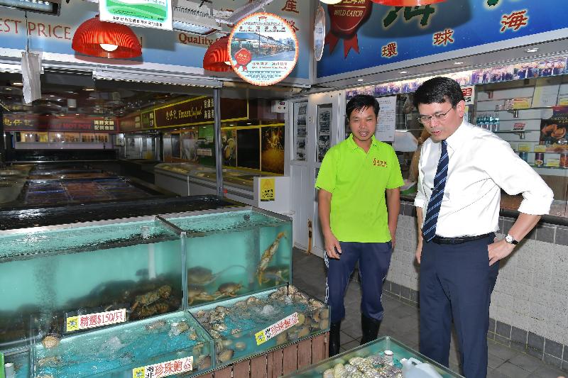 The Secretary for Commerce and Economic Development, Mr Edward Yau (right), tours Sam Shing Street (also known as Sam Shing Hui Seafood Market) and chats with a seafood store owner to better understand the business there during his visit to Tuen Mun District today (October 24).