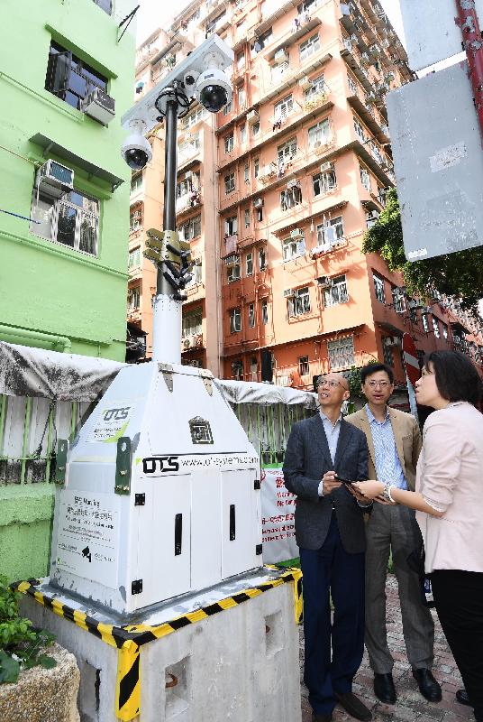 环境局局长黄锦星（左一）今日（十一月三日）到访大角咀惠安街，视察为打击非法弃置建筑废物而设的监察摄录系统试验计划的成果。