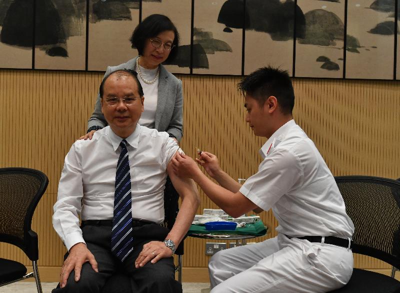 The Chief Secretary for Administration, Mr Matthew Cheung Kin-chung (front row, left), today (November 15) receives seasonal influenza vaccination by registered nurse Mr Leung Sin-fai (front row, right). Looking on is the Secretary for Food and Health, Professor Sophia Chan (back).